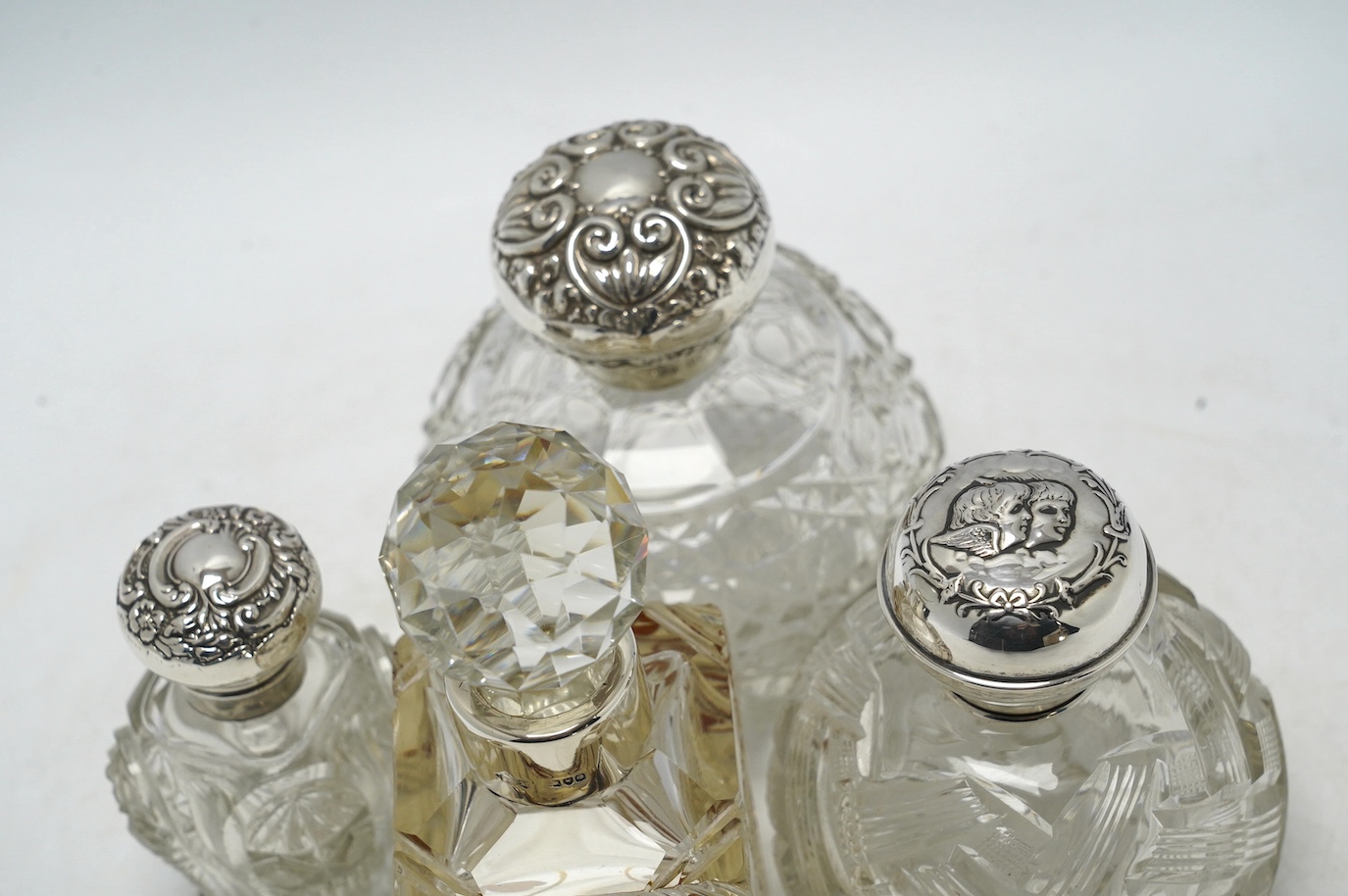 Four assorted early 20th century silver mounted glass scent bottles, tallest 16.1cm. Condition - fair